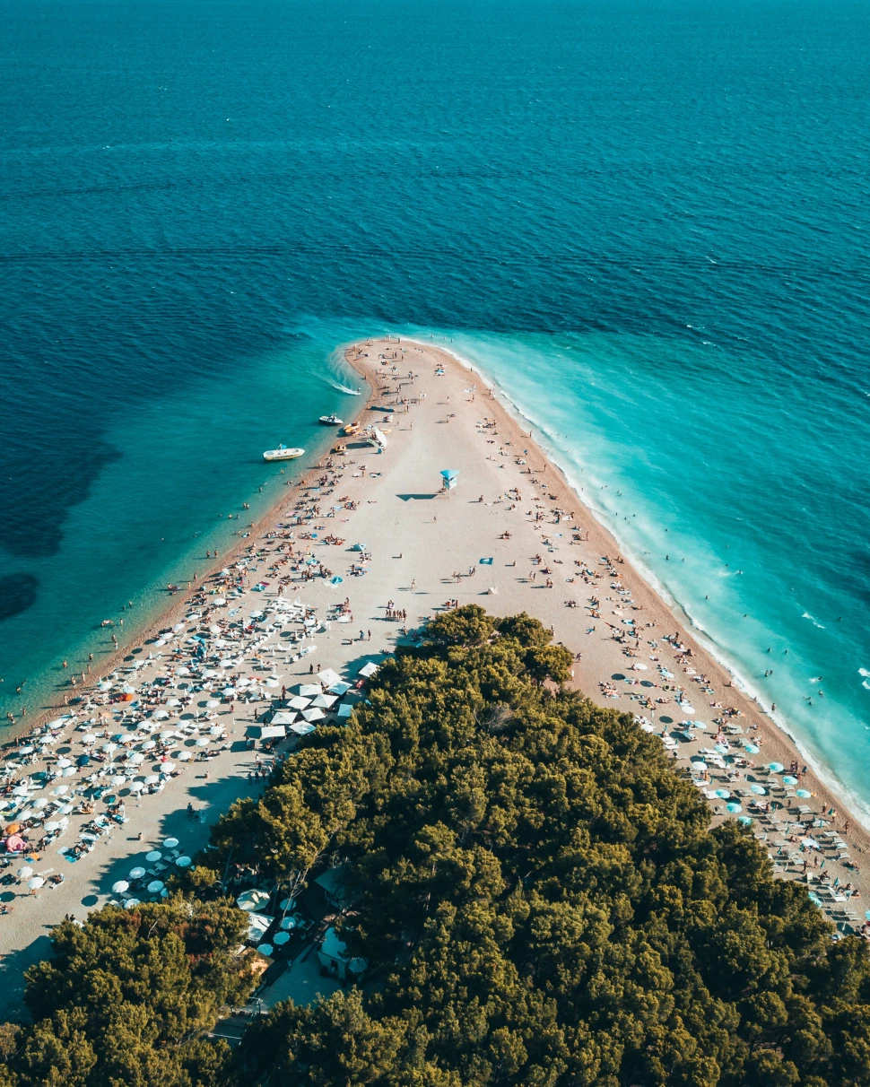 An azure sea and beach filled with people in Croatia. 