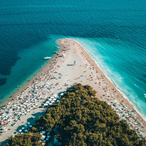 An azure sea and beach filled with people in Croatia. 