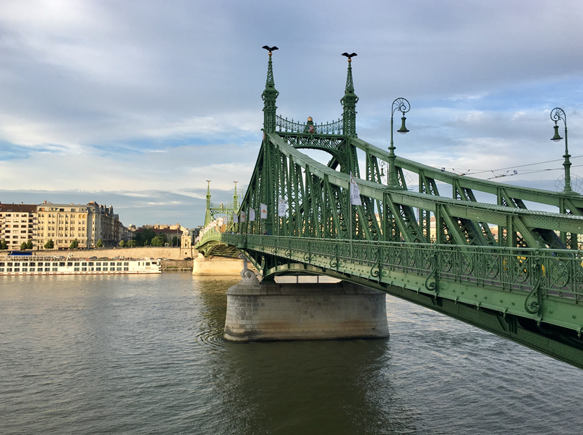 A green bridge on a water body.