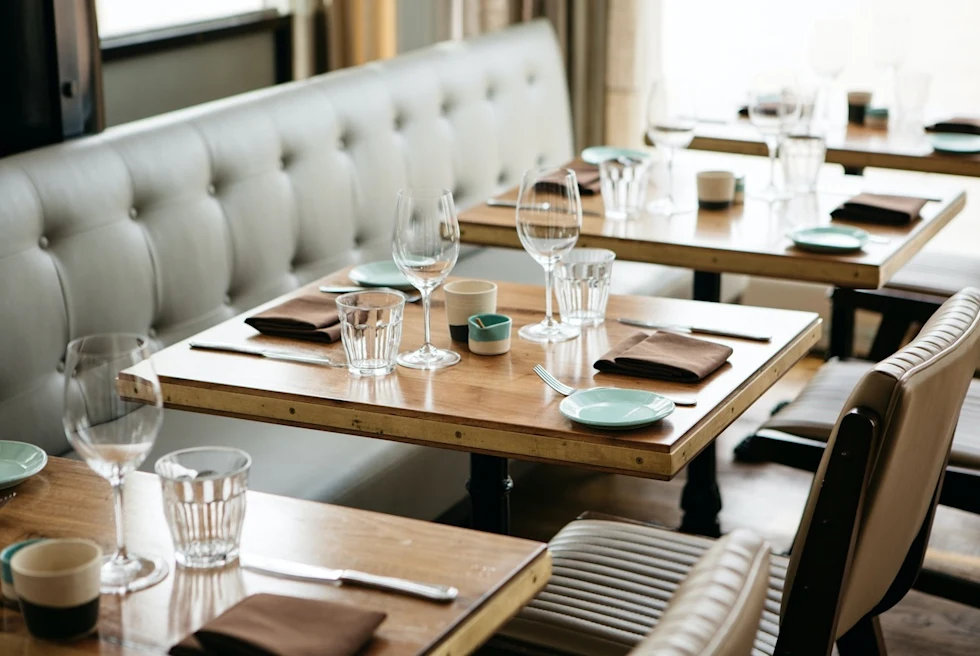 restaurant dining room with set wooden tables and a gray booth