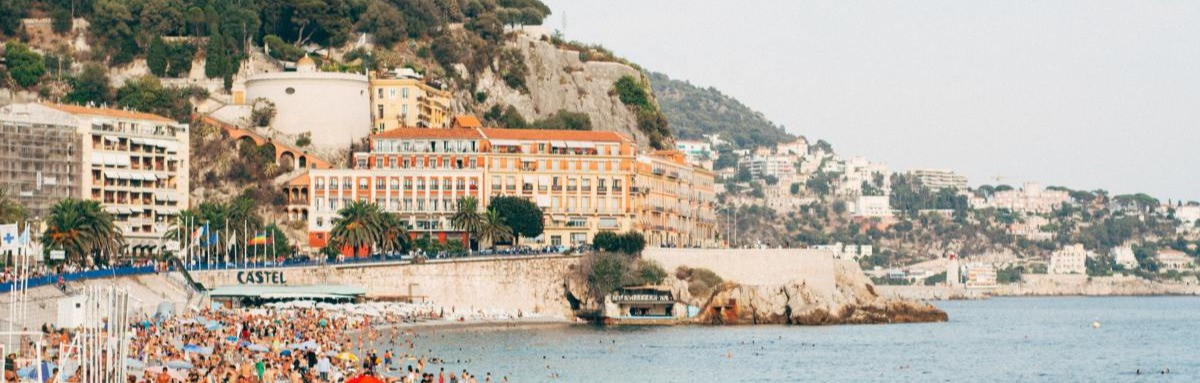 A popular beach on Nice against lush Mediterranean cliffs