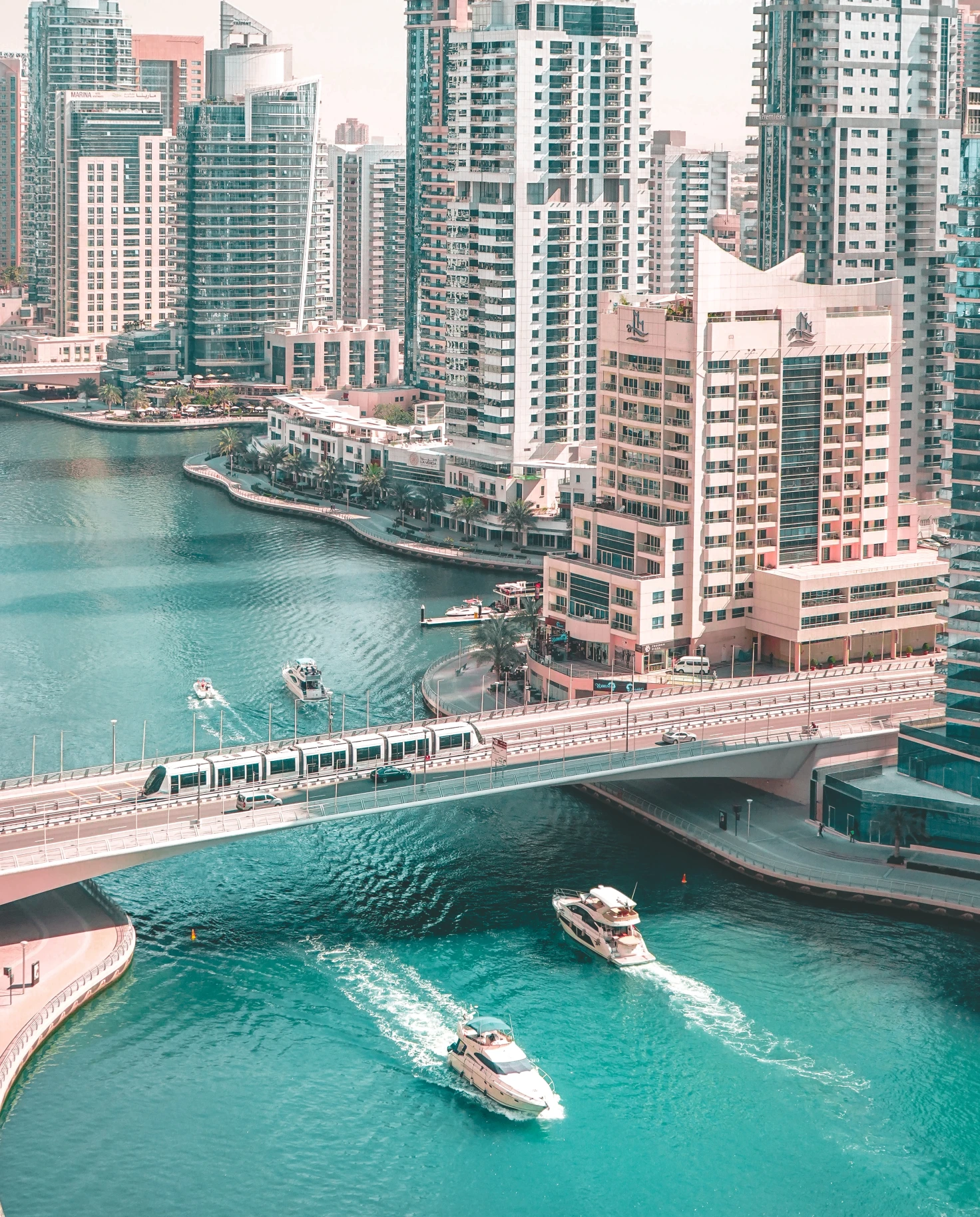 View of boats passing under bridge with buildings in the background in Dubai