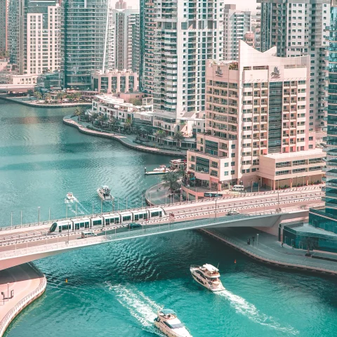 View of boats passing under bridge with buildings in the background in Dubai
