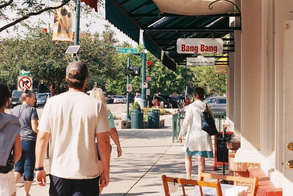 People walking in a local market of colorado and passing by a Cafe named Bang Bang