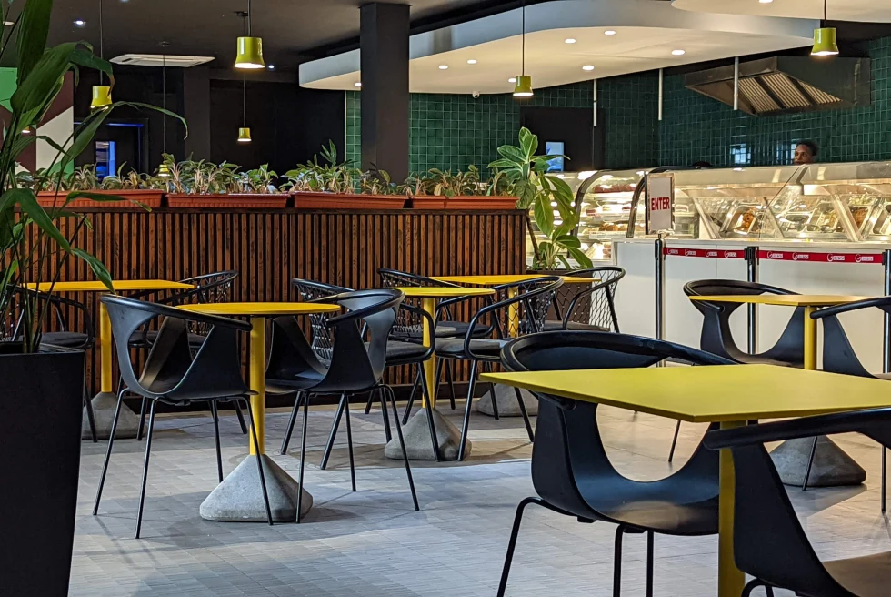 Restaurant with yellow tabels and black chairs.