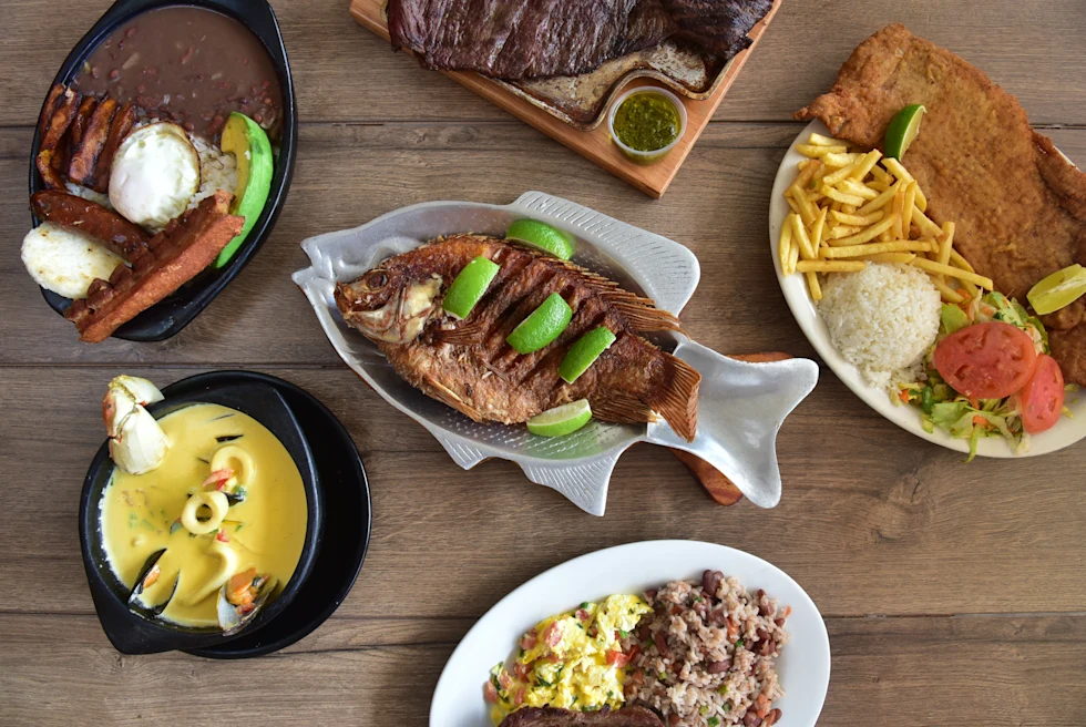 A table with a fried fish and other foods.