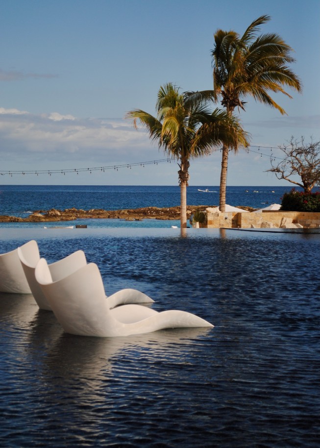 chairs in water with a palm tree in the background during daytime