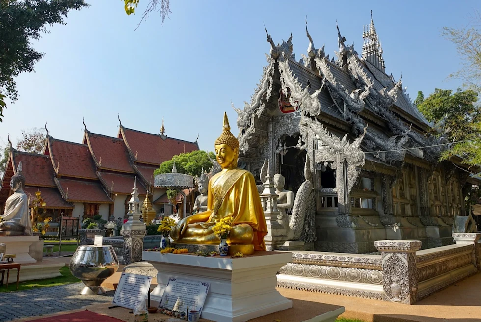 A golden statue in front of a gray colored hut.