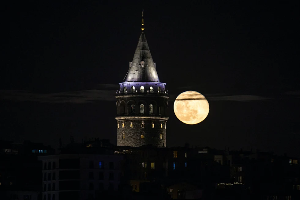 tip of a circular tower at night with full moon
