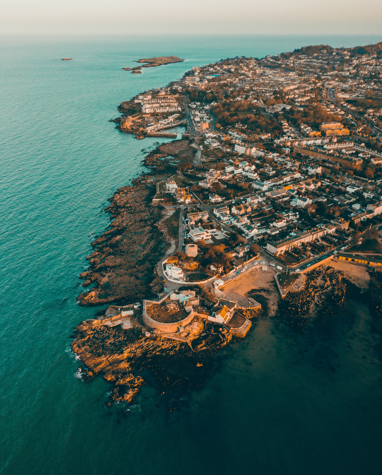 Birdseye view of Dublin, Ireland with clusters of tan buildings with blue ocean