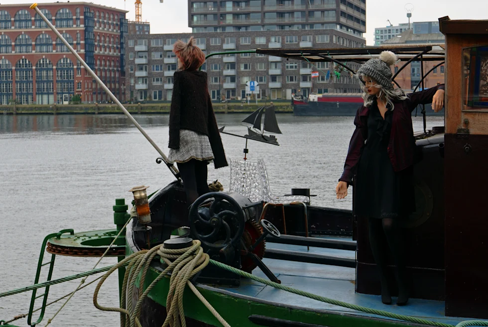 A house boat with two statues, anchored in water during daytime.