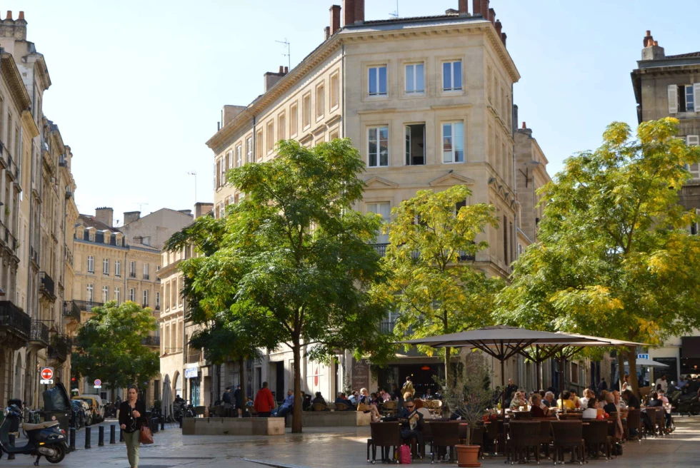 A street in France with outdoor little cafes and quaint buildings. 