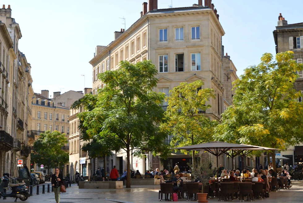 A street in France with outdoor little cafes and quaint buildings. 