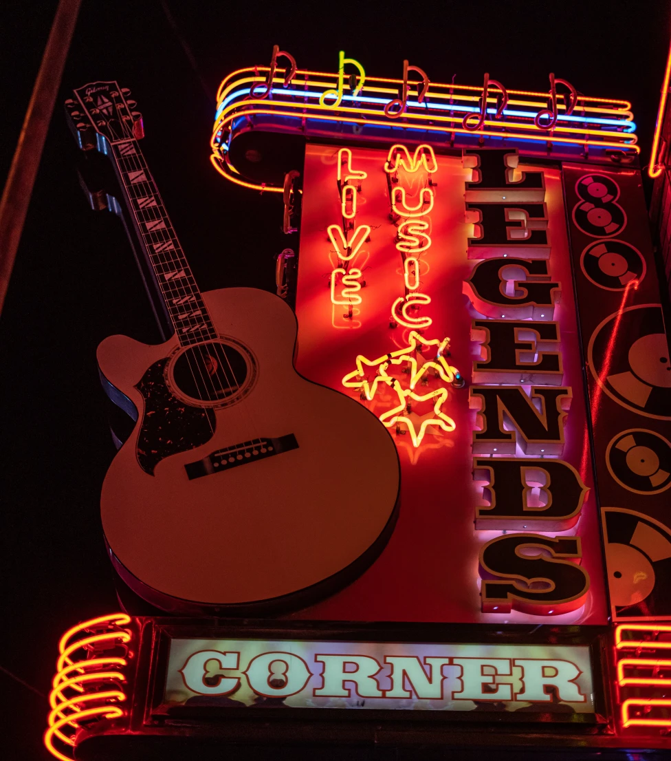 A wall with colorful lights and a writing saying LEGENDS CORNER and guitar hanging on it.
