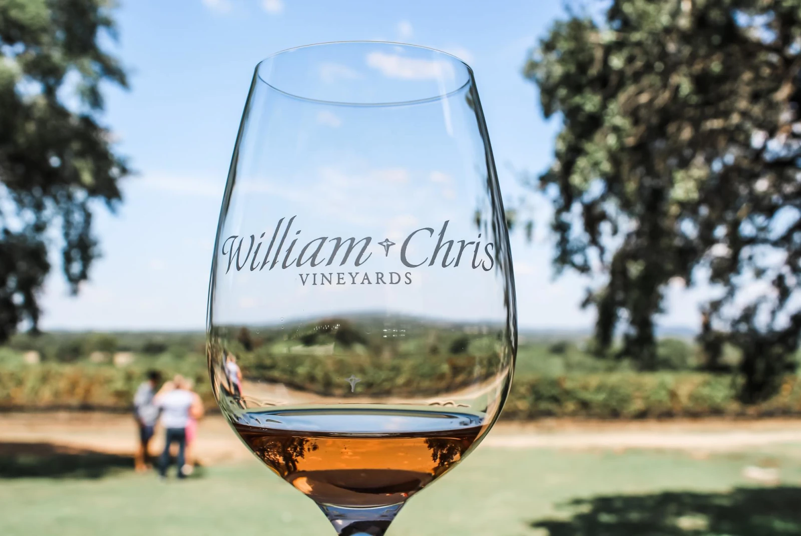 a glass of wine in front of a vineyard with a "william chris vineyards" logo 