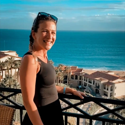 Travel Advisor Samantha Halseth in a brown shirt overlooking an ocean with houses.