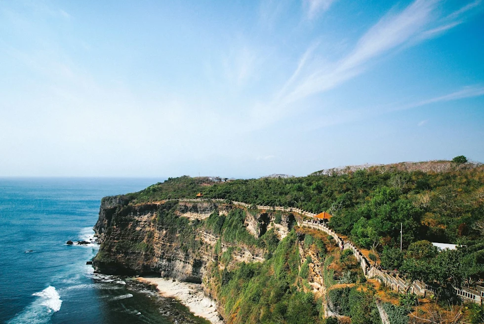 an ancient temple stretches along a cliff over the ocean on