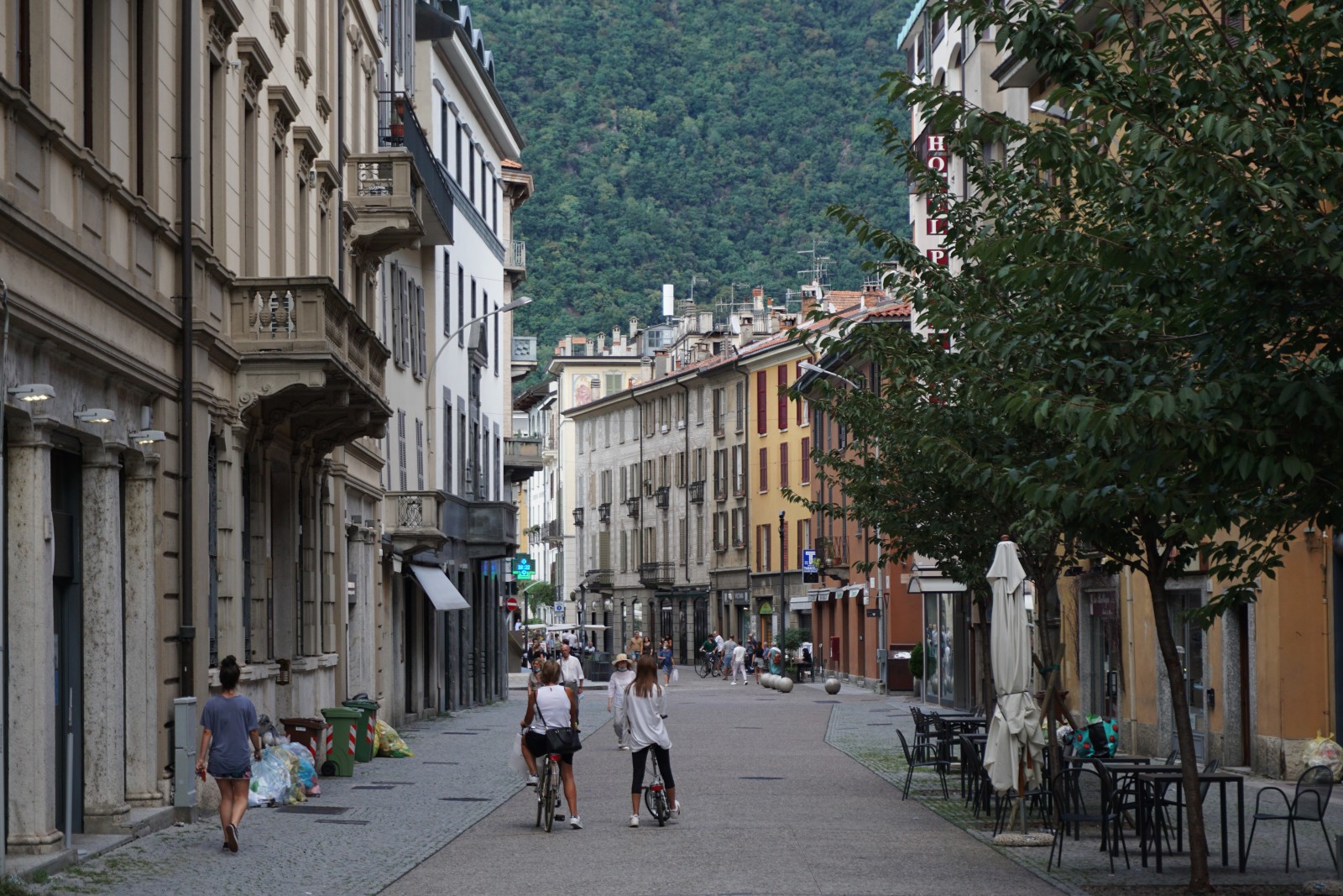 Four people walking in grey and white outfits in the streets of Como Town in Lake Como, Italy.