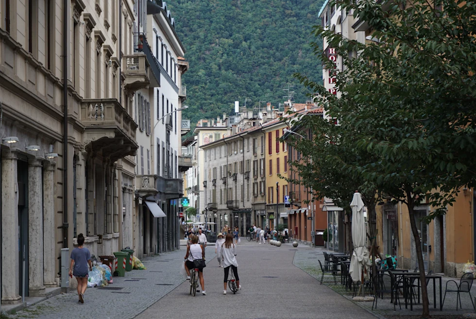 Four people walking in grey and white outfits in the streets of Como Town in Lake Como, Italy.