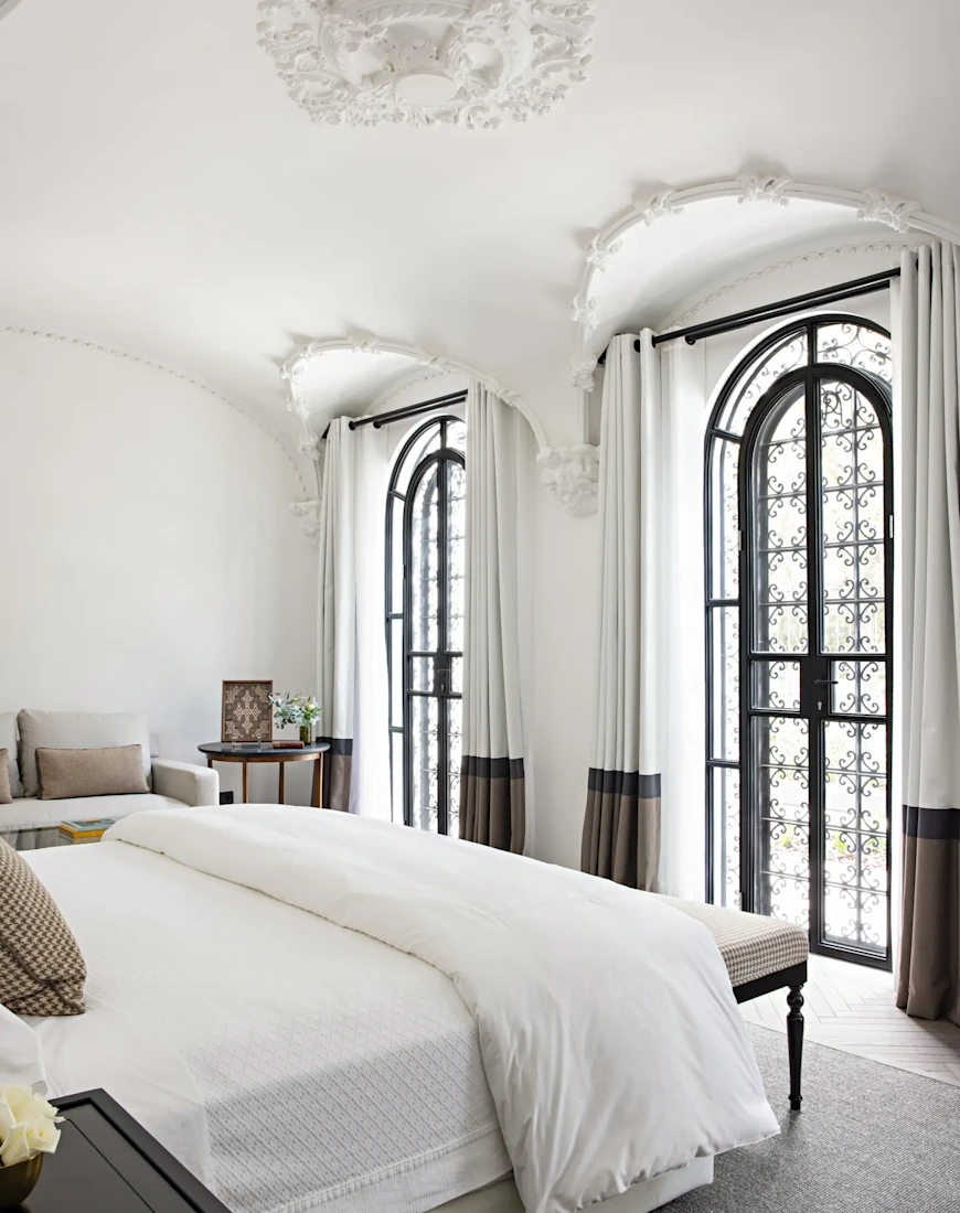 a luxe hotel room with floor-to-ceiling windows flanked by drapes