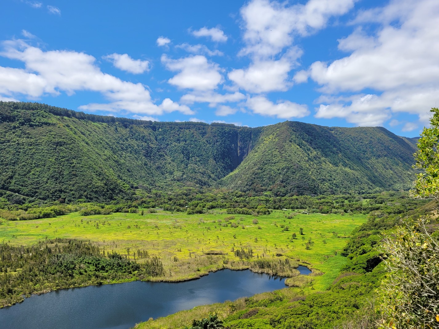 Green mountains and body of water with blue skies during daytime