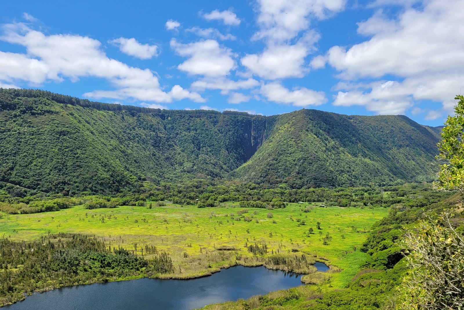 Green mountains and body of water with blue skies during daytime