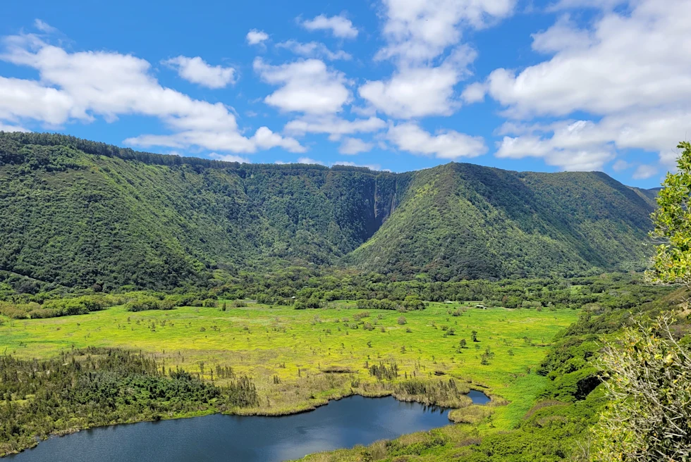 Green mountains and body of water with blue skies during daytime
