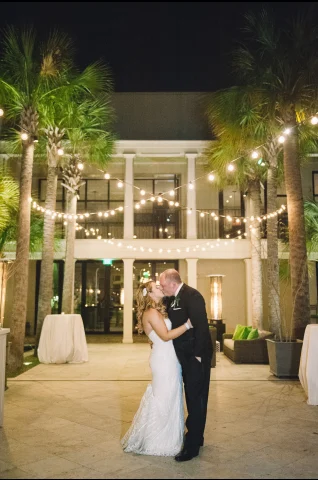 Couple in a courtyard kissing under the lights