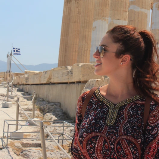 Travel Advisor Siane Chirpich in a red paisley top in front of ruins.