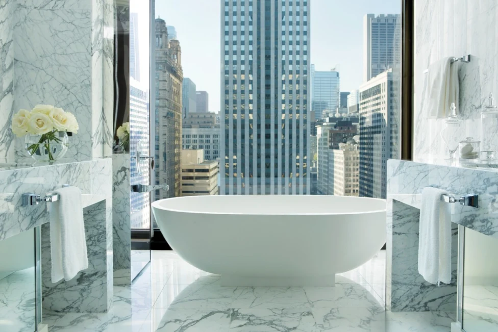 swanky marble bathroom with floor-to-ceiling windows and a large white tub