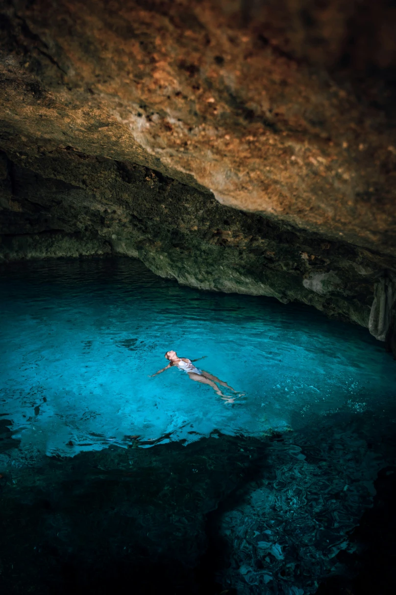A person floating in a body of water in a cave