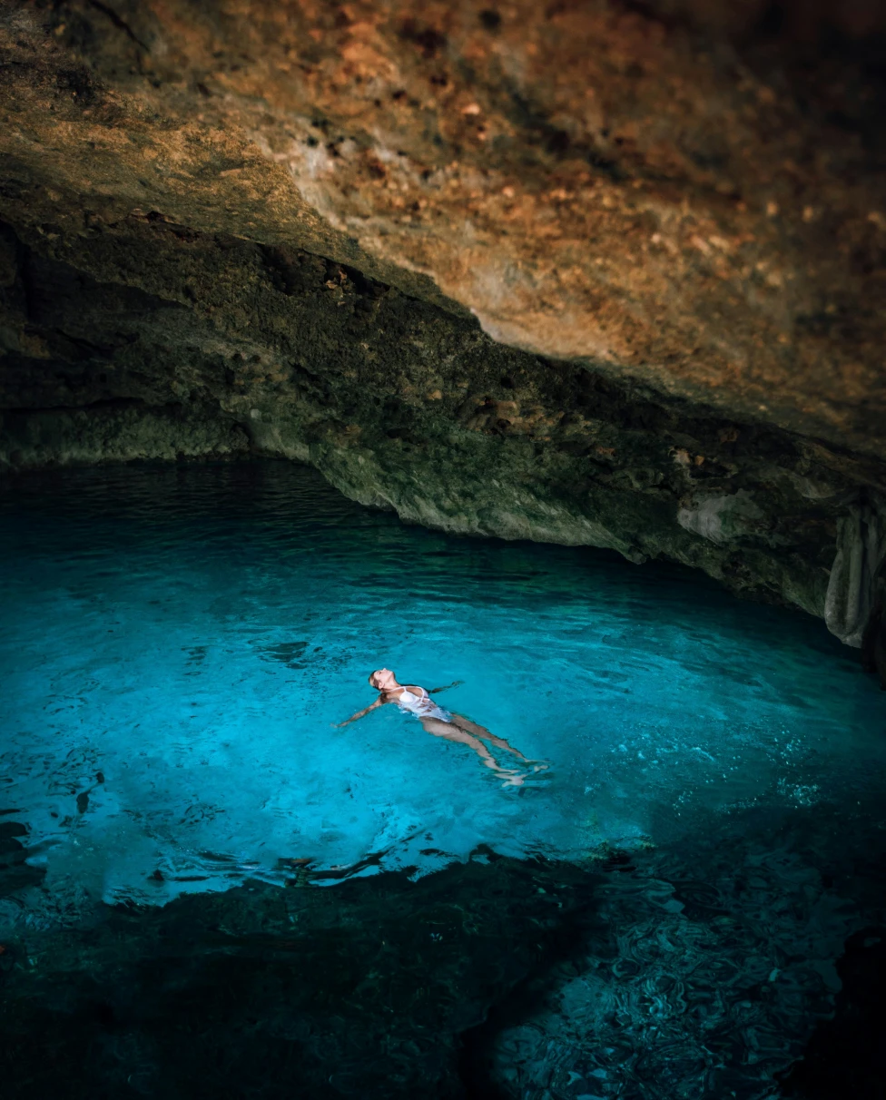 A person floating in a body of water in a cave