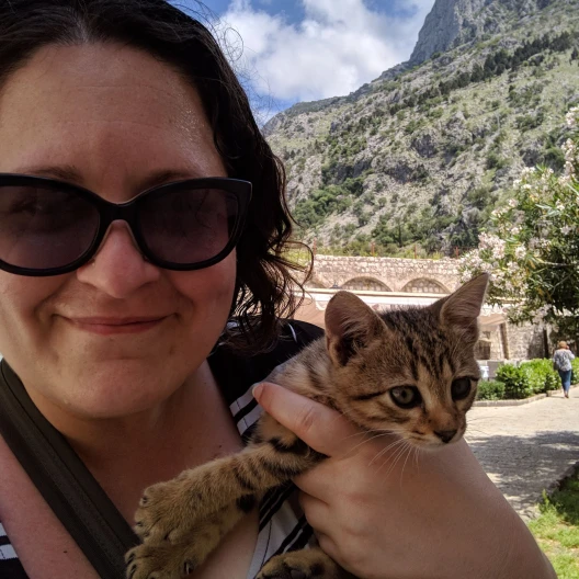 Travel advisor posing in a valley holding a cat