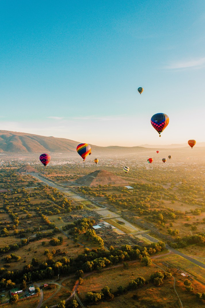 Colorful hot air balloons floating over a valley during daytime
