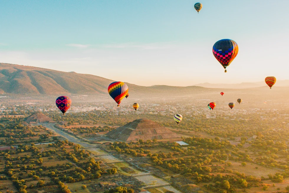 Colorful hot air balloons floating over a valley during daytime