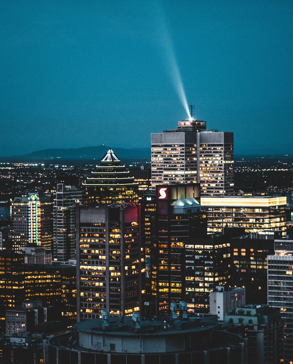 a city view of Montreal at night with dark blue skies and shiny tall gray buildings with yellow lights