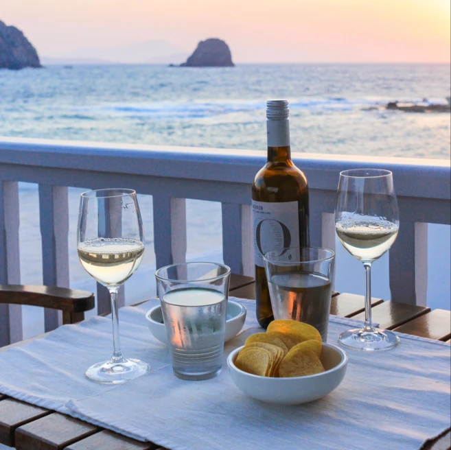white table with two glasses of wine overlooking a body of water