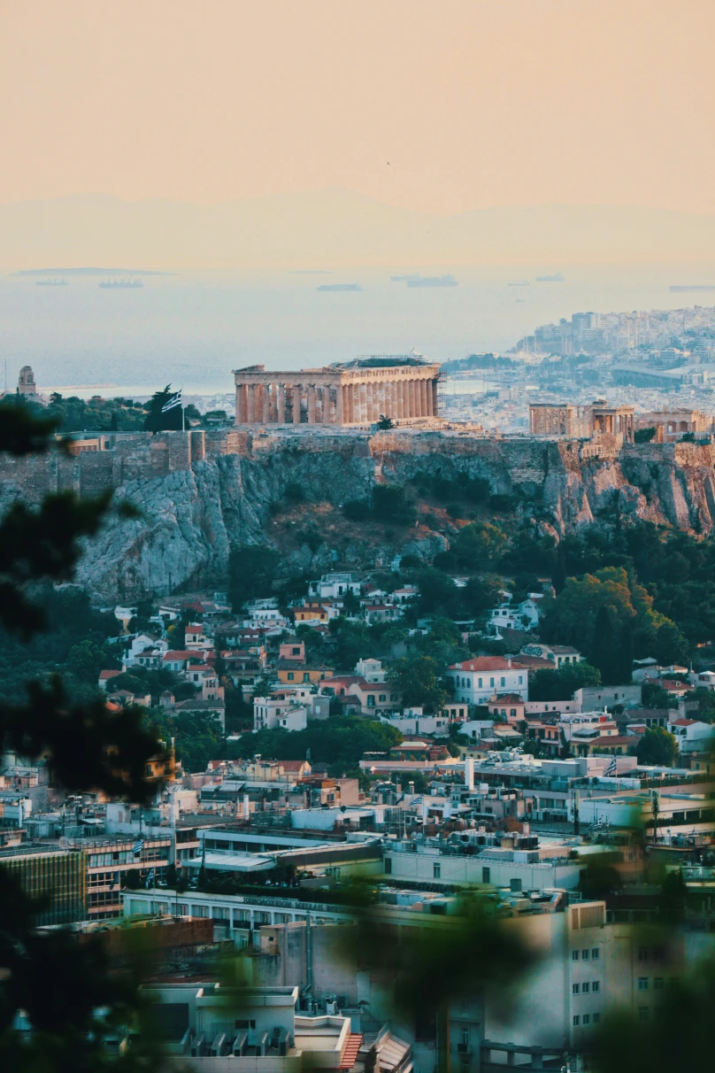 An aerial view of the city of Athens at sunset with the Acropolis on a hill.