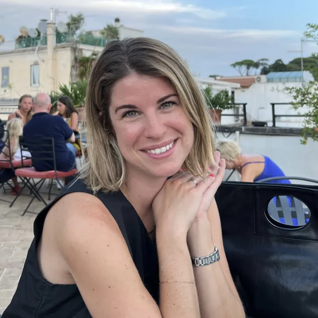 Travel advisor Jamie Fine in a black tank top smiling at an outdoor table