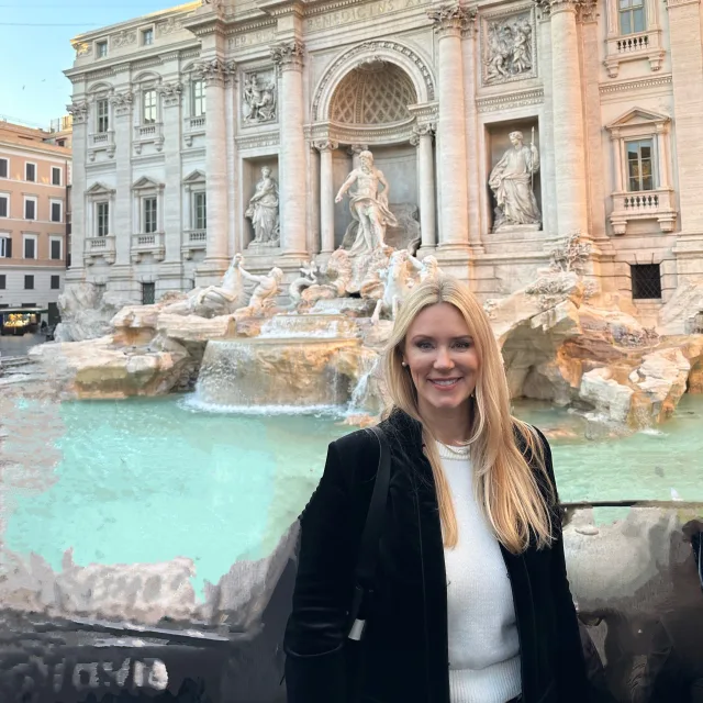 Travel Advisor Jennifer Lindner in a black and white shirt standing in front of the Trevi Fountain.