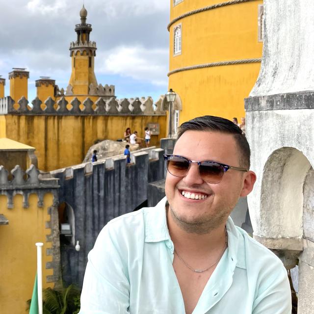 Fora travel agent Miguel Bautista wearing sunglasses with yellow building in background