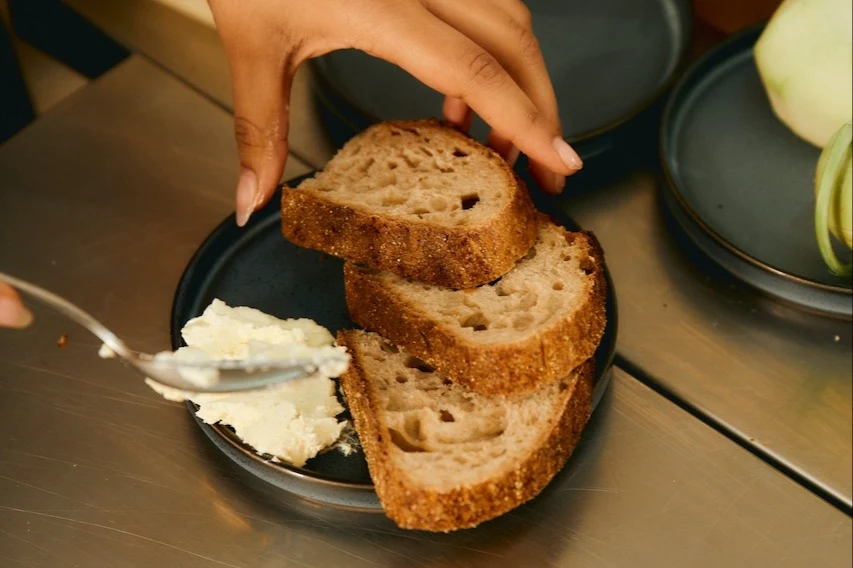 woman spreading white ricotta cheese on slices of bread