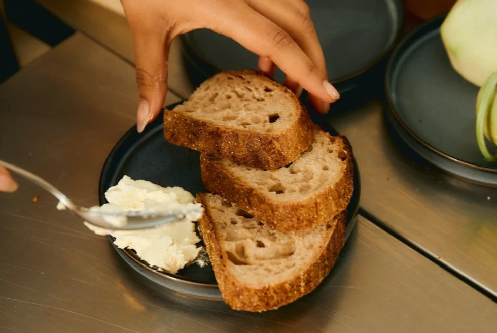 woman spreading white ricotta cheese on slices of bread
