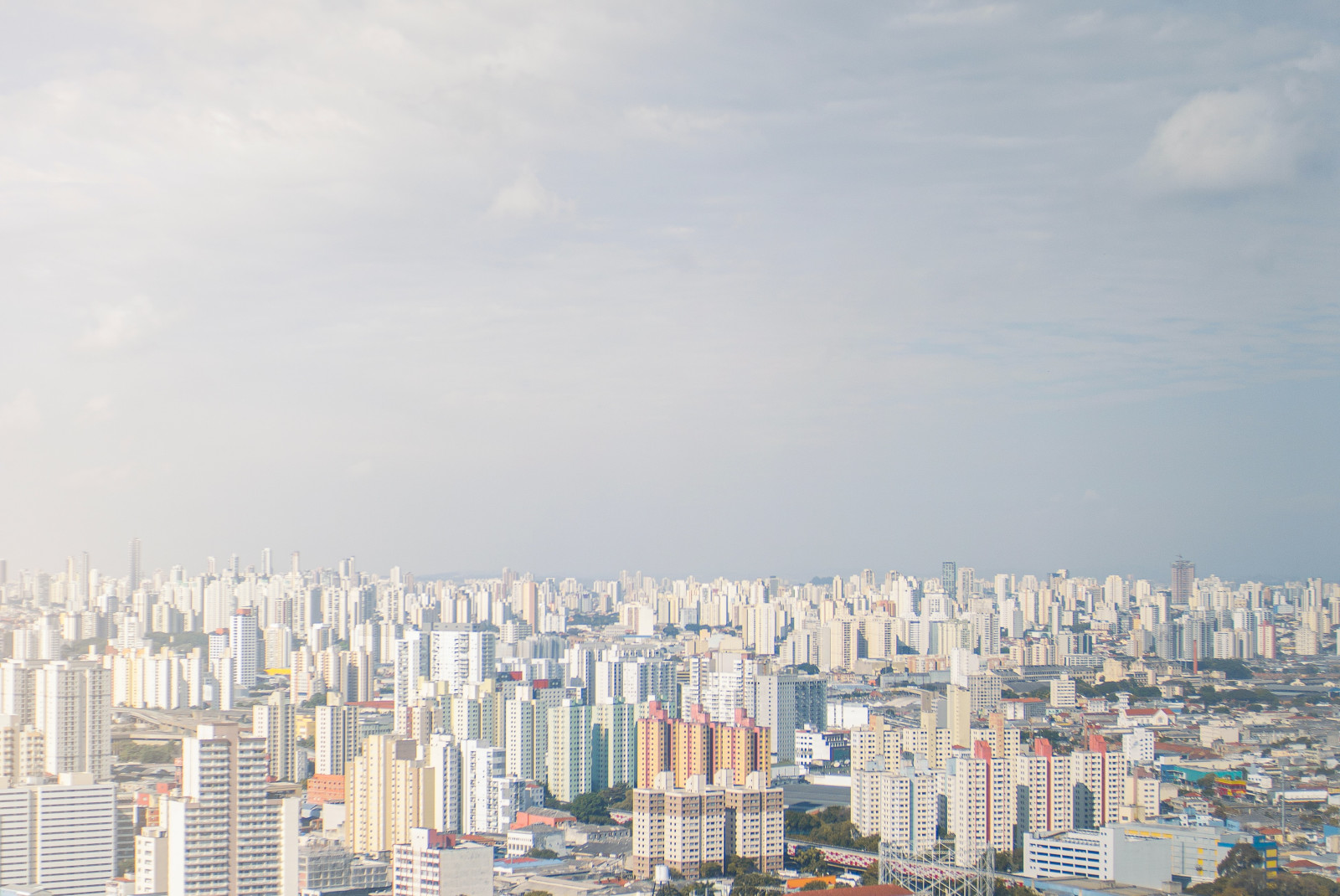 White building cityscape of São Paulo in Brazil with blue skies and green trees scattered amongst the buildings.