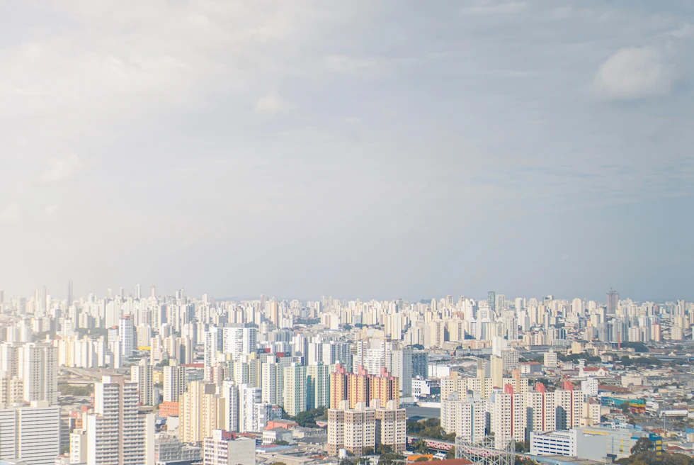 White building cityscape of São Paulo in Brazil with blue skies and green trees scattered amongst the buildings.