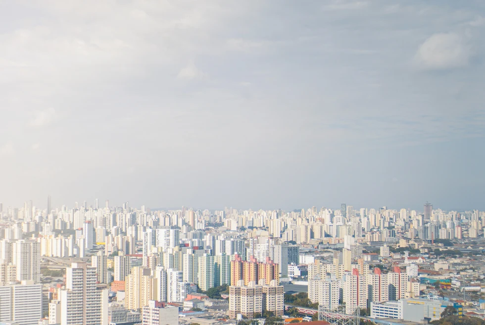 White building cityscape of São Paulo in Brazil with blue skies and green trees scattered amongst the buildings.