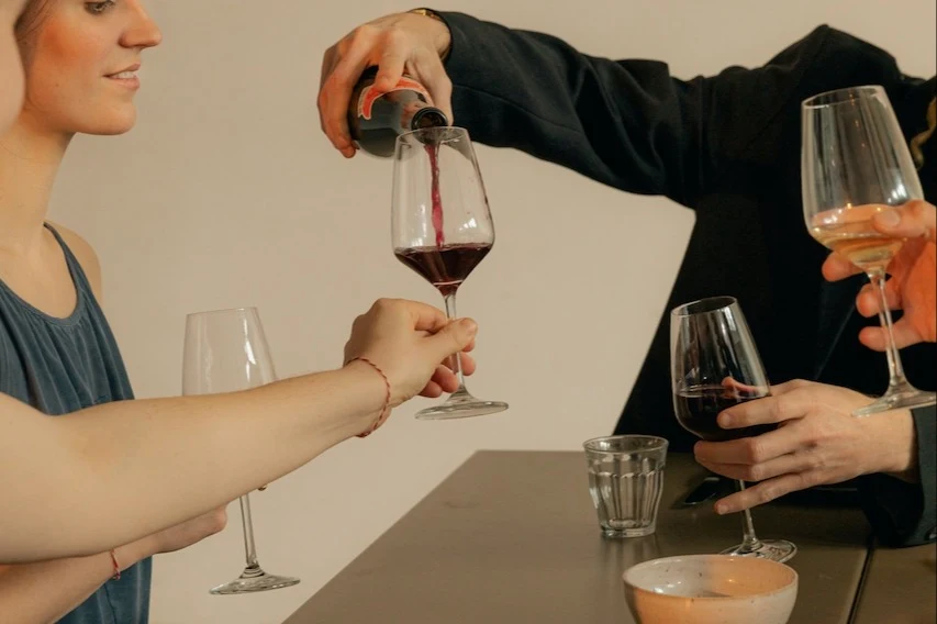 man pouring red wine into a woman's wine glass