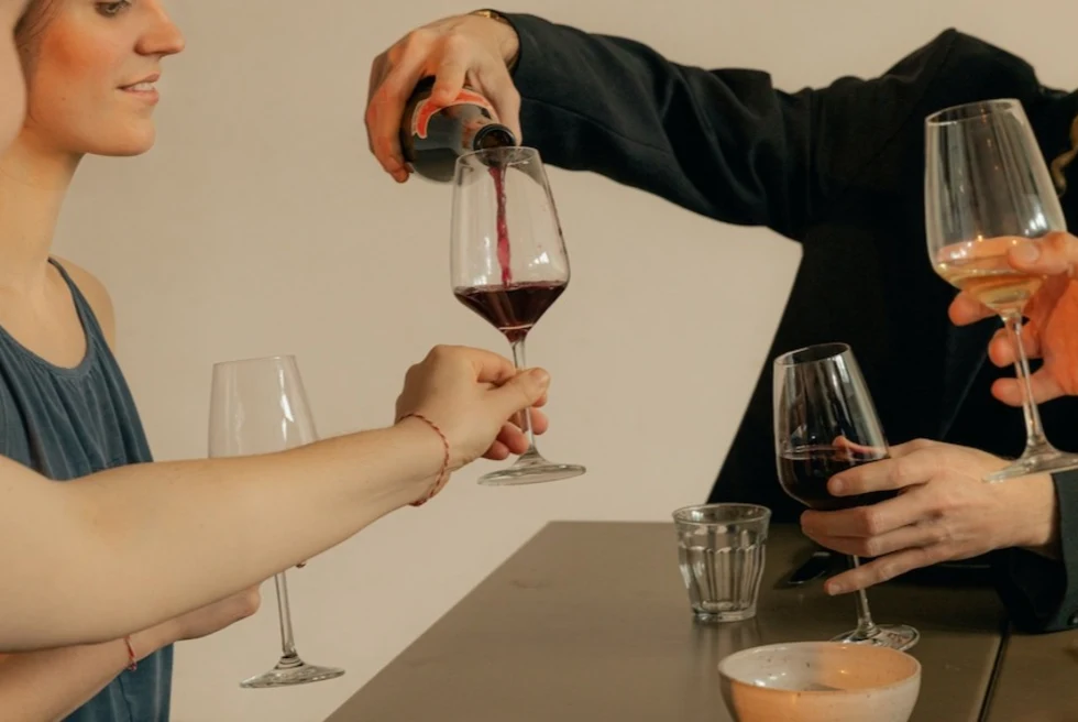 man pouring red wine into a woman's wine glass