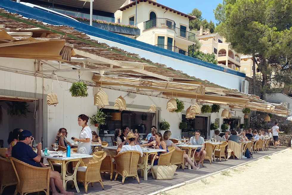 Tables and chairs next to the sand with blue skies during daytime