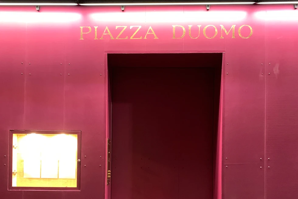 red door with gold lettering that reads, Piazza Duomo